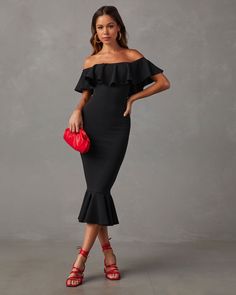 a woman wearing a black dress with ruffles on the shoulders and red purse