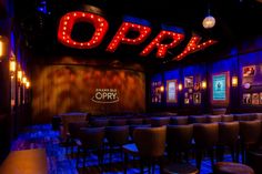 an empty restaurant with chairs and neon signs on the wall above it that says opry