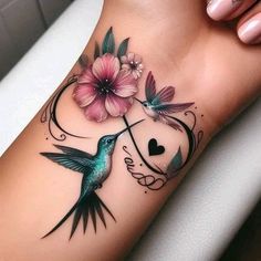 a hummingbird with flowers on its arm and heart in the middle is sitting next to a pink flower