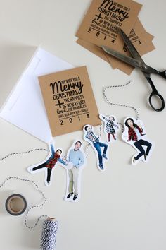 some paper cutouts are hanging on a table next to scissors and tape with the words merry christmas