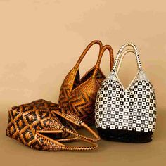 three handbags sitting next to each other on a brown surface, one is black and white