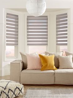 a living room filled with furniture and windows covered in blind shades on top of them