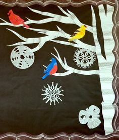 the birds are sitting on the tree branches in the wintertime scene with snowflakes