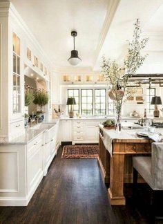 a large kitchen with white cabinets and wood floors