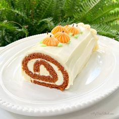 a piece of carrot roll on a white plate with green plants in the back ground