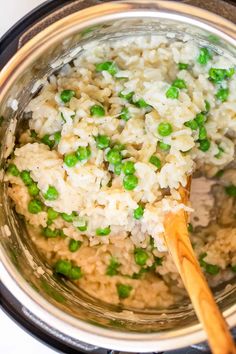 rice and peas are being cooked in an instant pot with a wooden spoon on the side