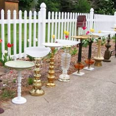 a white picket fence with lots of different types of birdbathes on top of it