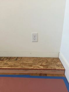 an electrical outlet on the side of a wall in a room with hard wood flooring