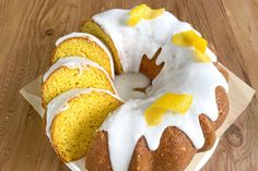 a bundt cake with white icing and lemons on it sitting on a wooden table