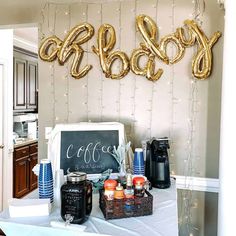 a baby shower table with balloons and confetti on it, including coffee cups