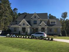 a white car parked in front of a large house with lots of windows and landscaping