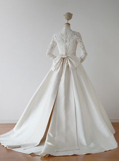 the back of a wedding dress on display in a room with white walls and wooden flooring