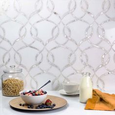 a bowl of cereal sits on a plate next to a glass jar with milk and strawberries