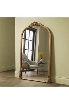 a large mirror sitting on top of a wooden floor next to a chair and table