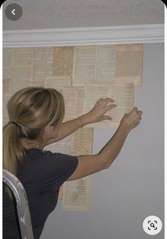 a woman is leaning against the wall with her arms stretched out and reading a book