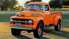 an orange truck parked on top of a grass covered field