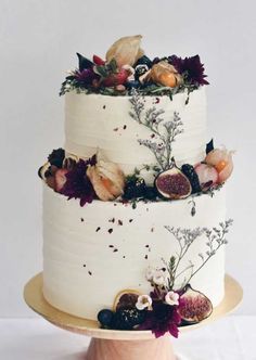 a three tiered cake decorated with flowers and fruit