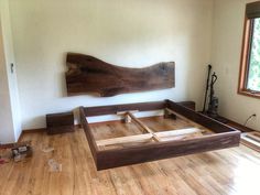 a wooden bed frame sitting on top of a hard wood floor next to a window