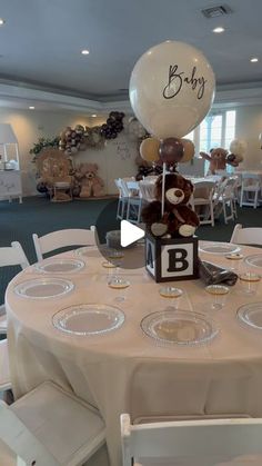 a teddy bear centerpiece on top of a table at a baby's first birthday party