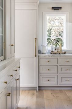 a kitchen with white cabinets and gold handles on the door knobs is seen in this image