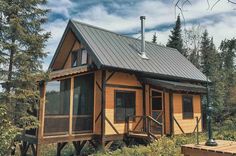 a small wooden cabin in the woods with a porch and stairs leading up to it