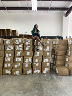 a woman sitting on top of boxes in a warehouse