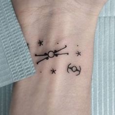 a small tattoo on the wrist of a person with a clock and stars around it