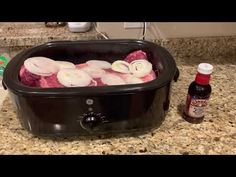 the food is being cooked in the crock pot on the kitchen counter next to bottles of ketchup