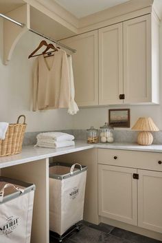 a laundry room with white cabinets and baskets