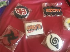 nine decorated cookies in plastic wrappers on a red tablecloth with the word naruto printed on them