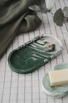 two pieces of soap sitting on top of a green tray next to a piece of wax