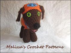 a crocheted brown dog with green eyes and a hat on it's head