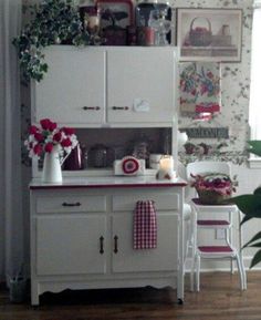 a kitchen with white cabinets and flowers on the counter