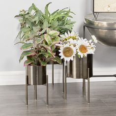 three metal planters with flowers in them on the floor