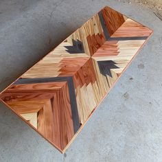 a large wooden tray with black and brown designs on it sitting on the cement floor