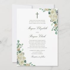 a white and green floral wedding card with a cross on the front, surrounded by greenery