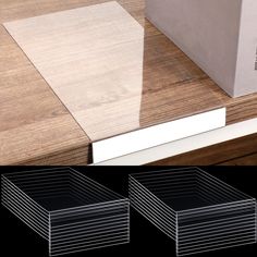 three clear boxes sitting on top of a wooden table next to a white box and two black boxes