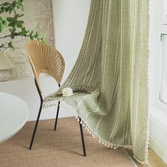 a chair sitting next to a window with a blanket on it's back and a plant in the corner