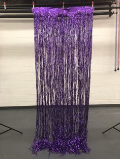 purple streamers are hanging from the ceiling in front of a white wall and black floor