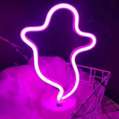 a purple neon sign sitting on top of a white basket next to a pink wall