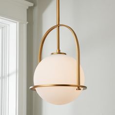 a light fixture hanging from the ceiling in a living room with white walls and windows