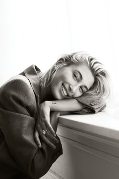 a black and white photo of a woman leaning on a window sill