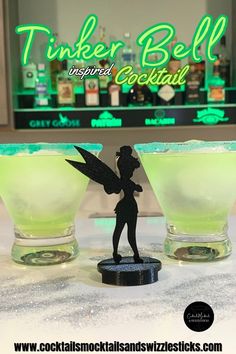 This image shows two green cocktails with a green rim in front of a bar with a Tinerbell Sillouhette in between them and silver glitter scattered around Live Action Peter Pan, Cocktail Movie, Disney Themed Food, Faith Trust And Pixie Dust, Fruity Alcohol Drinks, Peter Pan And Wendy