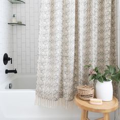 a white bath tub sitting next to a wooden table with a potted plant on it