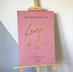 an easel with a pink sign on it that says the wedding of lanana and mark