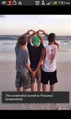 three boys standing on the beach holding hands in the shape of a heart with their hands