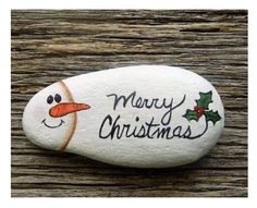 a rock with a snowman face painted on it and merry christmas written on it