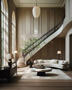 an elegant living room with wood paneling and white couches in front of a spiral staircase