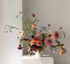 a white vase filled with lots of colorful flowers