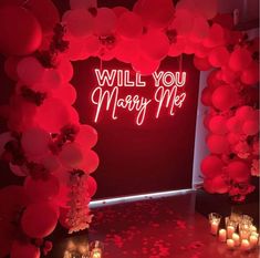 a room with candles and balloons that say will you marry me? on the wall